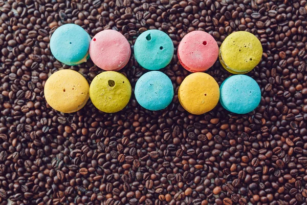 Tatlı ve kahve çekirdekleri arka plan üzerinde renkli Fransızca macaroons — Stok fotoğraf
