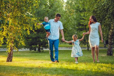 Mutlu genç aile yürüyüş ve having fun parkta Dört Kişilik