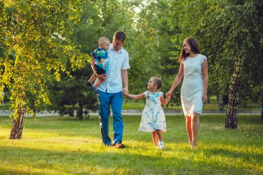 Mutlu genç aile yürüyüş ve having fun parkta Dört Kişilik