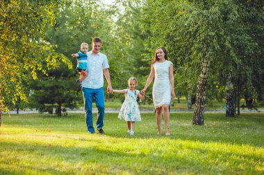 Mutlu genç aile yürüyüş ve having fun parkta Dört Kişilik