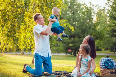 Parkta piknik üzerinde dört genç mutlu aile