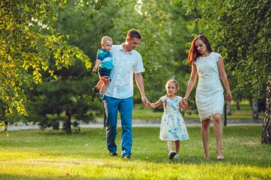 Mutlu genç aile yürüyüş ve having fun parkta Dört Kişilik