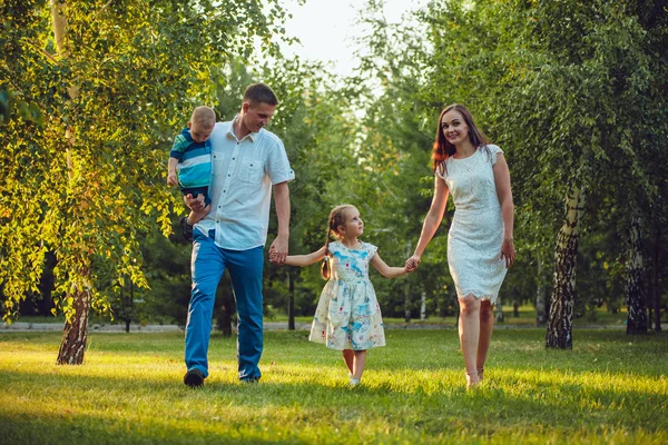 Glad ung familj på fyra personer gå och ha kul i parken — Stockfoto