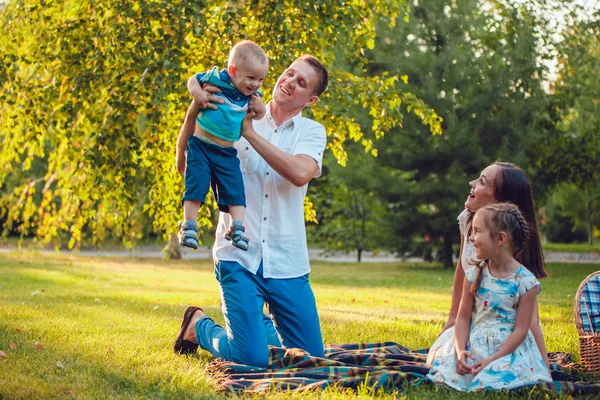 Молодая счастливая семья из четырех человек на пикнике в парке — стоковое фото