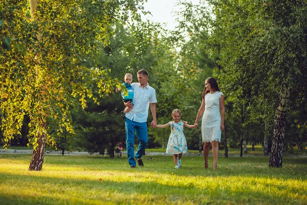 Glad ung familj på fyra personer gå och ha kul i parken — Stockfoto