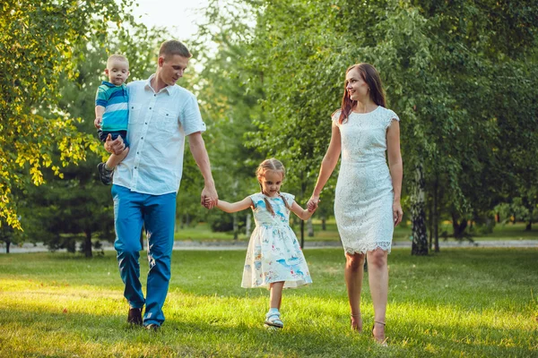 Glad ung familj på fyra personer gå och ha kul i parken — Stockfoto