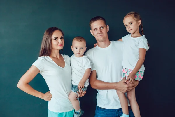 Ung familj fyra stående i vit skjorta över svart bakgrund — Stockfoto