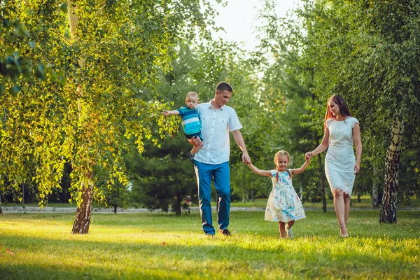 Счастливая молодая семья из четырех человек гуляет и развлекается в парке — стоковое фото