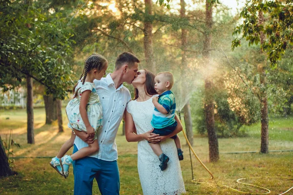 Glad ung familj på en bakgrund av vatten i parken, föräldrar håller barnen i handen — Stockfoto