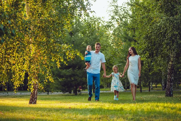 Glad ung familj på fyra personer gå och ha kul i parken — Stockfoto