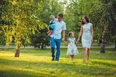 Mutlu genç aile yürüyüş ve having fun parkta Dört Kişilik