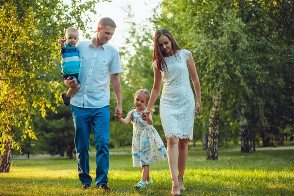 Glad ung familj på fyra personer gå och ha kul i parken — Stockfoto