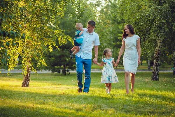 Glad ung familj på fyra personer gå och ha kul i parken — Stockfoto