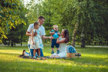 Parkta piknik üzerinde dört genç mutlu aile