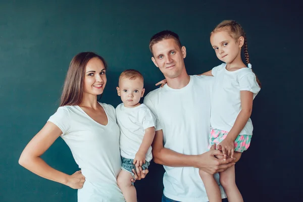 Jeune famille de quatre personnes debout en chemise blanche sur fond noir — Photo