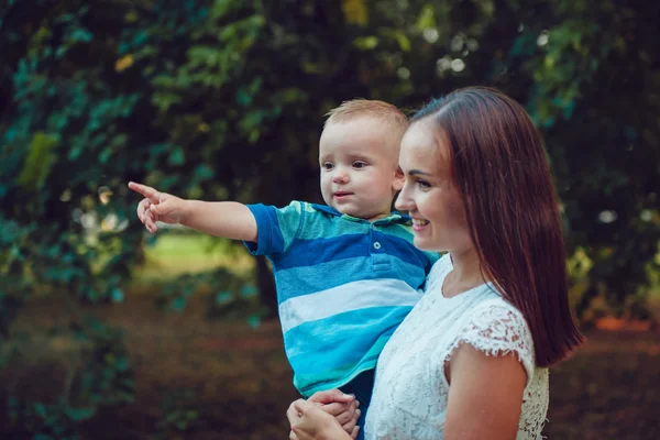 Ung kvinna håller sin son i armar i parken — Stockfoto