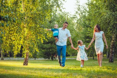 Mutlu genç aile yürüyüş ve having fun parkta Dört Kişilik
