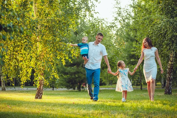 Glad ung familj på fyra personer gå och ha kul i parken — Stockfoto