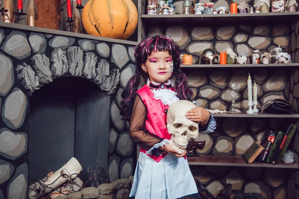 Девушка в костюме ведьмы череп в его руке в пейзаже Хеллоуин — стоковое фото