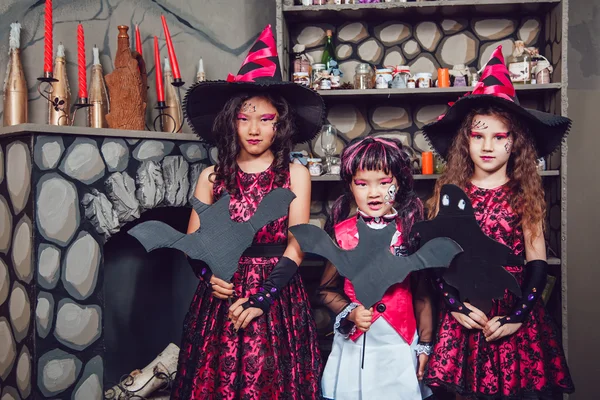 Três meninas em trajes de bruxa estão em decorações de Halloween — Fotografia de Stock