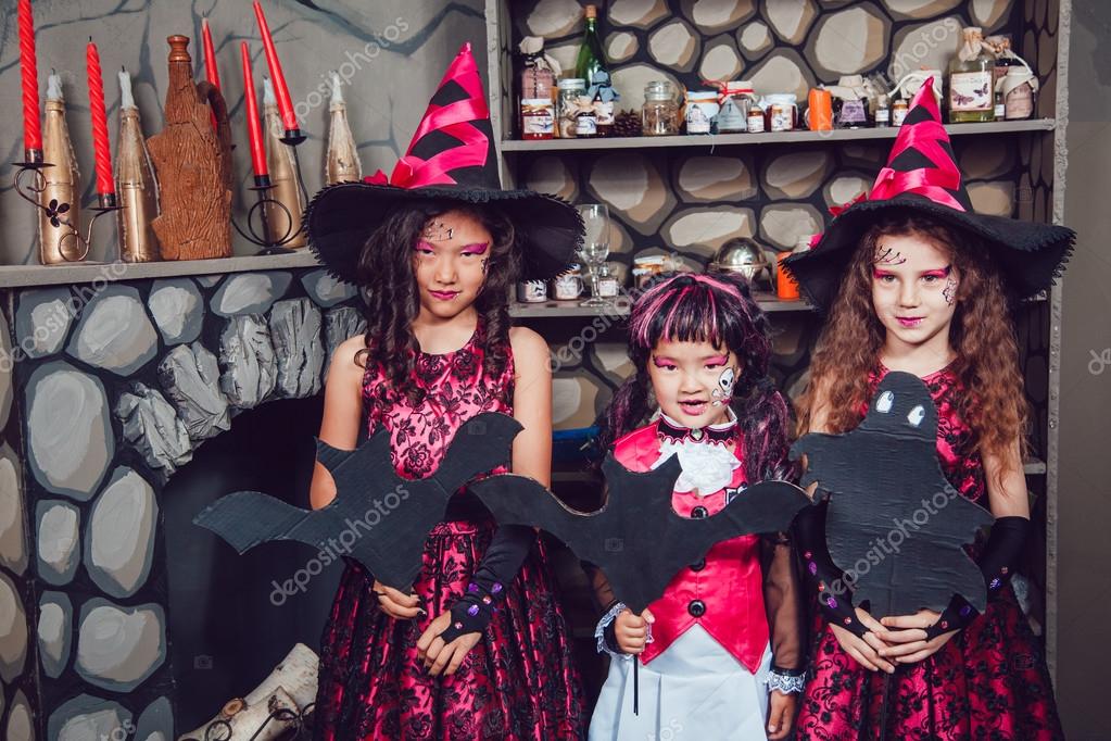 Tres chicas en trajes de bruja están en decoraciones de Halloween