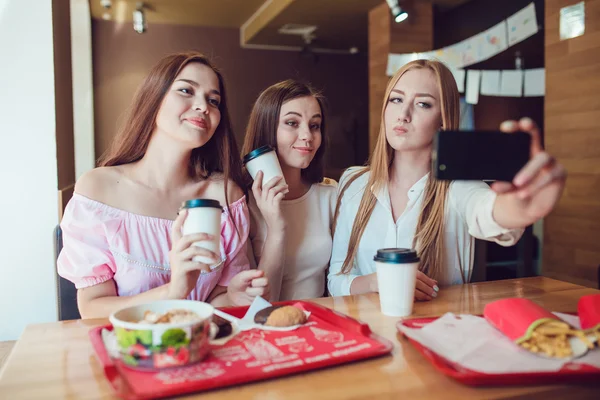 Три молодые девушки делают селфи в ресторане быстрого питания — стоковое фото