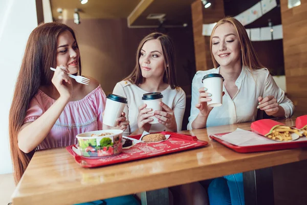 Trzy młode dziewczyny wesoły, jedzenie w restauracji fast food — Zdjęcie stockowe