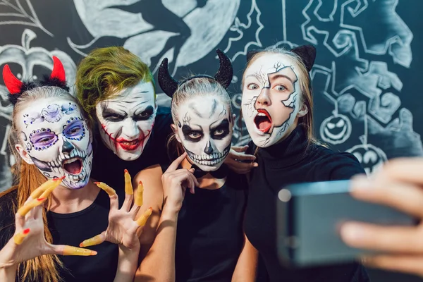 Üç kız ve bir adamın Cadılar Bayramı'nda çıktığını, yüz buruşturma yapmak selfie — Stok fotoğraf