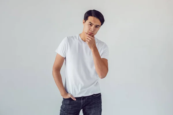 Attractive asian man in white t-shirt stands on white background. — Stock Photo, Image