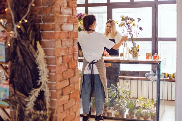 Floristería niñas recogen ramos de flores en su escritorio en una tienda de flores. — Foto de Stock