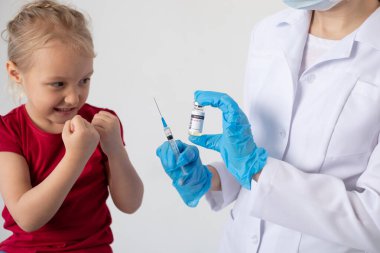 Bir çocuk elinde şırınga ve kovid aşısı olan bir doktora karşı kendini savunur..