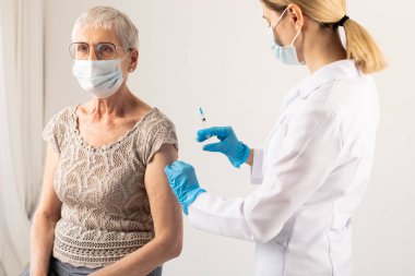 Yaşlı bir hastaya kovid 19 aşısı yapan bir doktor. Aşılama kavramı.
