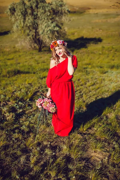 Flicka i röd klänning går på fältet — Stockfoto