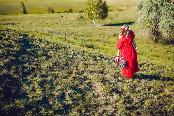 Meisje in de rode jurk loopt op het veld — Stockfoto