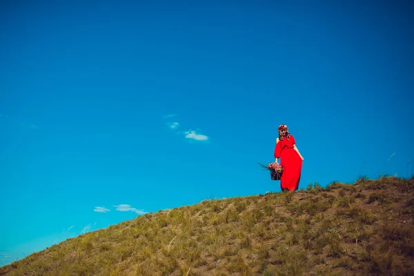 Mädchen im roten Kleid geht aufs Feld — Stockfoto