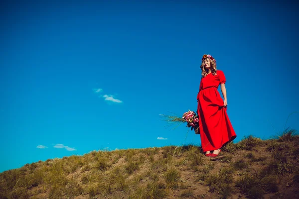 Chica en el vestido rojo está caminando en el campo —  Fotos de Stock