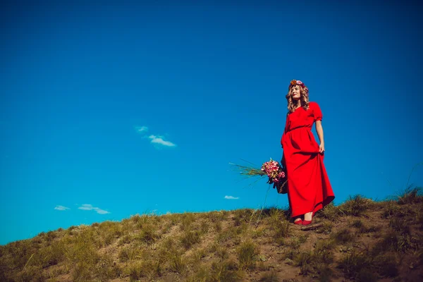 Fille dans la robe rouge marche sur le terrain — Photo