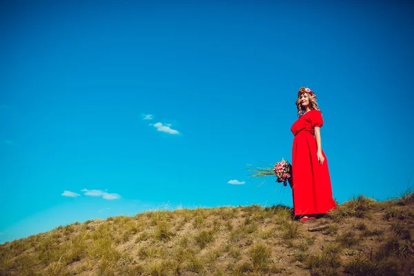 Fille dans la robe rouge marche sur le terrain — Photo