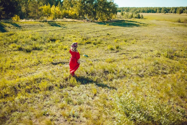 Fille dans la robe rouge marche sur le terrain — Photo