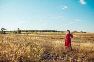 Kırmızı elbiseli kız sahada yürüyor