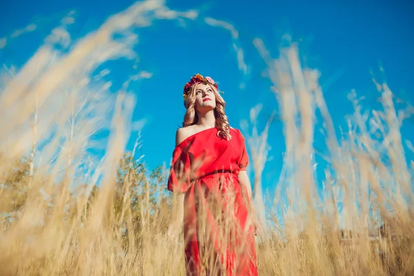 Girl in the red dress is walking On the field — Stock Photo, Image