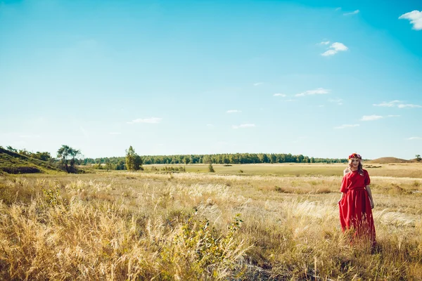Chica en el vestido rojo está caminando en el campo —  Fotos de Stock