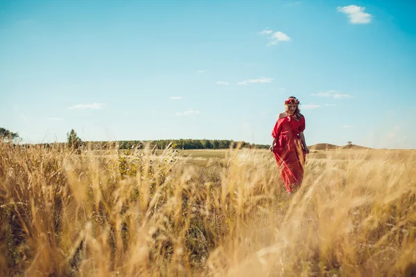 Girl in the red dress is walking On the field — Stock Photo, Image