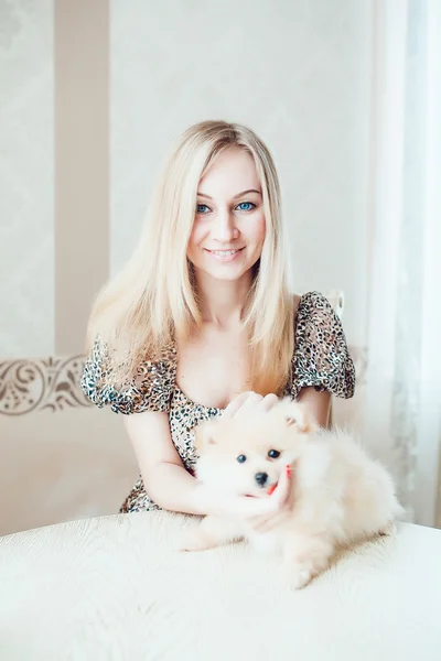 Mulher loira bonita com seu cão em um belo interior — Fotografia de Stock