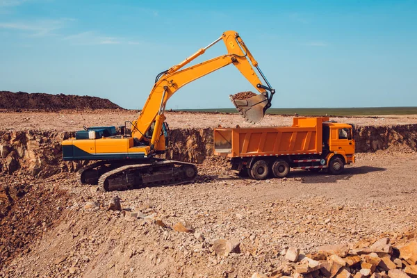 Escavadeira carrega cascalho em um caminhão em uma pedreira de pedra esmagada — Fotografia de Stock