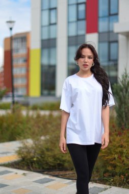 Şık bir kadın, canlı ve renkli mimarisi olan modern bir şehir ortamında kendine güvenerek poz veriyor.