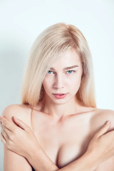 Vacker blond med gröna ögon på en ljus bakgrund. Hon ser in i kameran. Fashionabla hårfärg. En bra manikyr. — Stockfoto