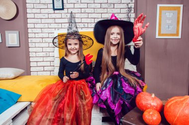 Girls, dressed up in Halloween costumes, show emotions of witches and vampires.