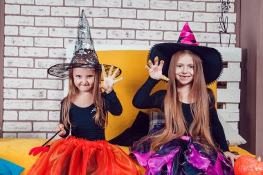 Girls, dressed up in Halloween costumes, show emotions of witches and vampires.