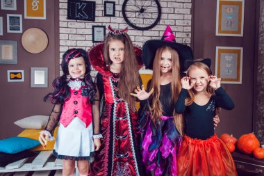 Girls, dressed up in Halloween costumes, show emotions of witches and vampires.